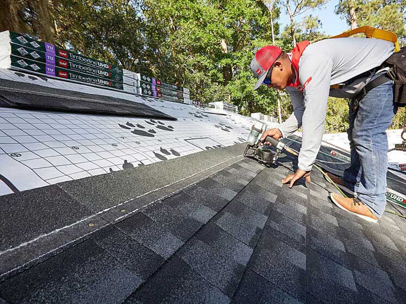 Single worker on a large roof doing repairs at the very top