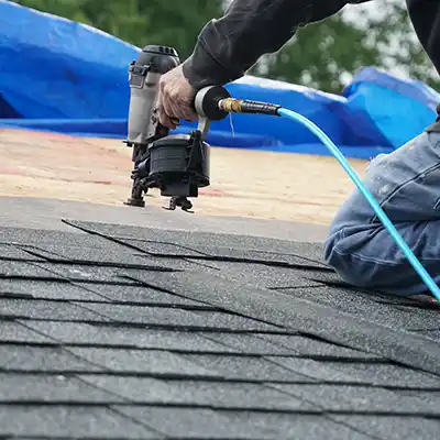 Roofer installing new gray shingles on a home